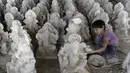 Perajin muda menyelesaikan pembuatan patung Dewa Ganesha di sebuah bengkel di pinggiran Hyderabad, India, Senin (29/6/2020). Patung Dewa Ganesha banyak ditemukan di berbagai penjuru India termasuk Nepal, Tibet, dan Asia Tenggara. (NOAH SEELAM/AFP)