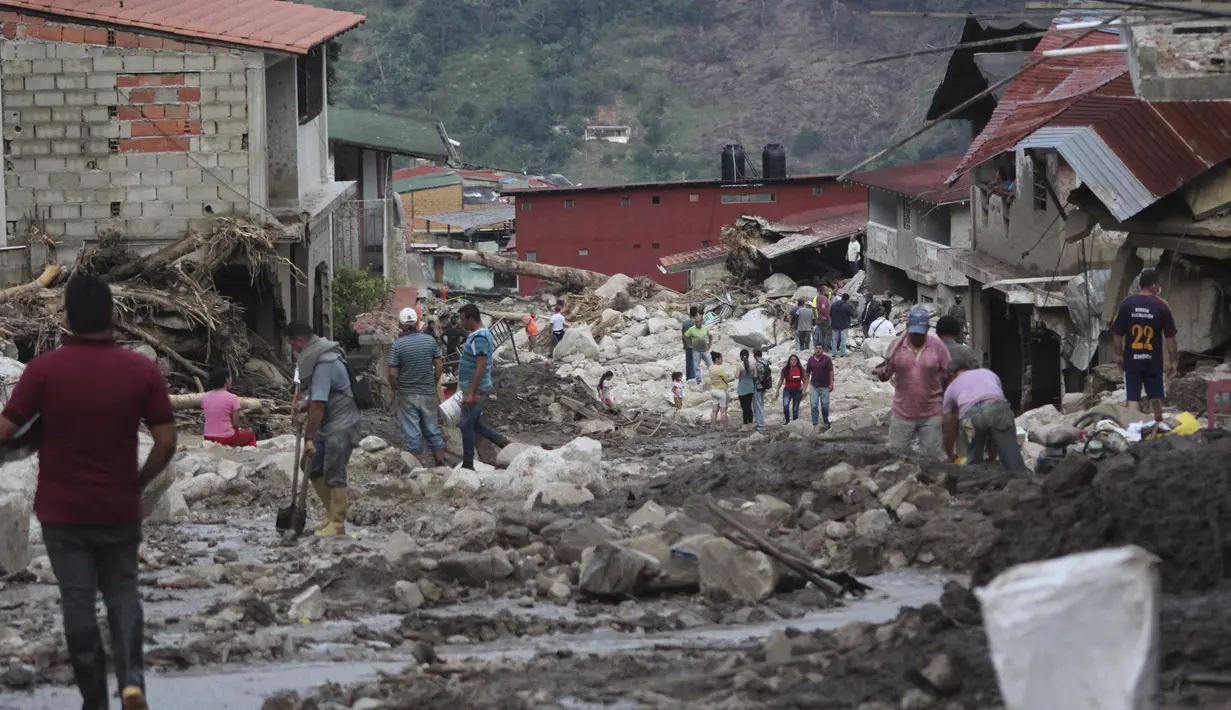 Orang-orang berjalan di jalan yang rusak akibat banjir dan tanah longsor yang dipicu hujan lebat di Tovar, negara bagian Merida, Venezuela, Kamis (26/8/2021). Gubernur Merida, Ramon Guevara, mengatakan lebih dari 1.200 rumah telah hancur dan 17 orang masih dalam pencarian. (AP Photo/Luis Bustos)
