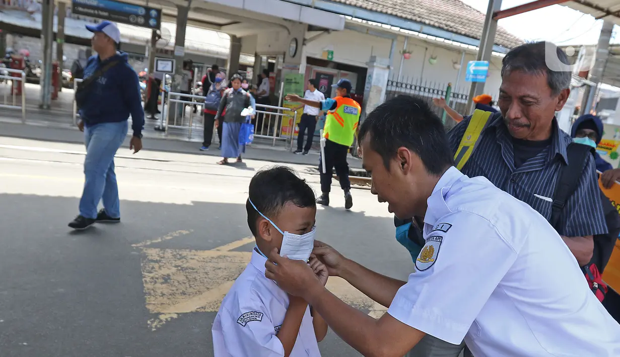 Petugas memasangkan masker ke seorang anak saat sosialisasi pencegahan virus  corona yang digelar PT KAI Daop 1 melalui Rail Clinic  di stasiun kereta Depok, Jumat (6/3/2020).  (Liputan6.com/Herman Zakharia)