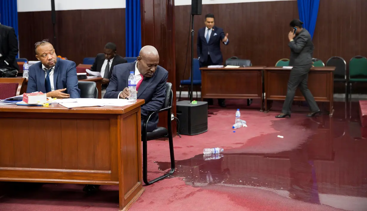 Anggota parlemen bekerja di tengah genangan air hujan yang membasahi lantai Gedung Parlemen Haiti, Port-au-Prince, Haiti, Rabu (21/8/2019). Kejadian itu terlihat ketika para anggota parlemen sedang memperdebatkan proses impeachment terhadap Presiden Haiti Jovenel Moise. (AP Photo/Dieu Nalio Chery)