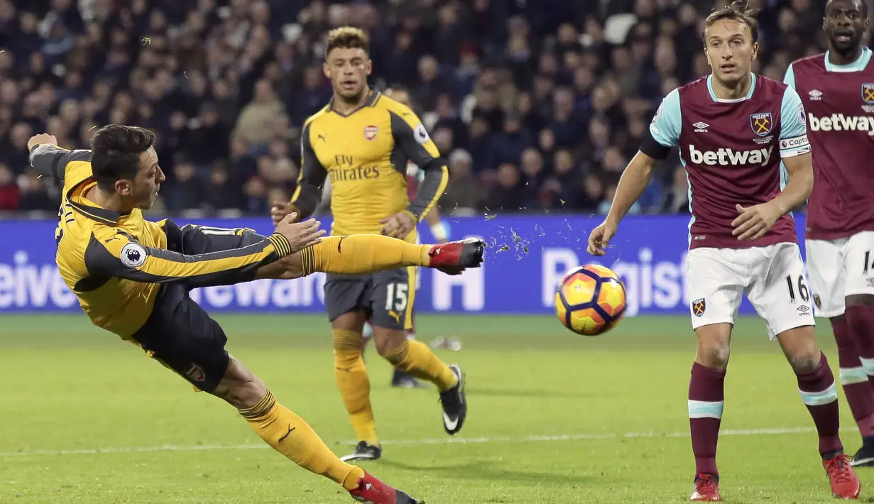 Pemain Arsenal, Mesut Ozil, melepaskan tendangan saat melawan West Ham United pada laga Liga Inggris di Stadion London, Sabtu (3/12/2016). (AP Photo/Tim Ireland)