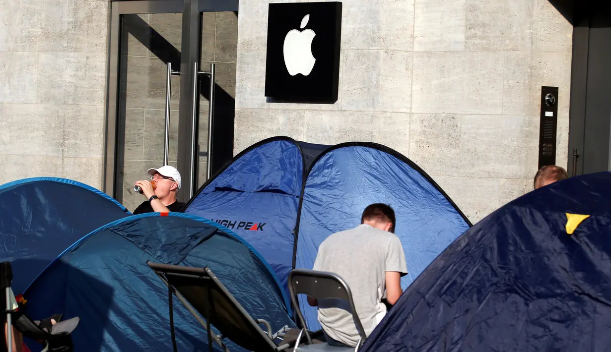 Pecinta iPhone sedang menunggu di samping tenda untuk membeli Apple iPhone 7 yang baru dirilis di depan toko Apple Berlin, Jerman (12/09). Sambal menunggu mereka menist waktu dengan membaca dan bermain tablet. (REUTERS/Fabrizio Bensch)