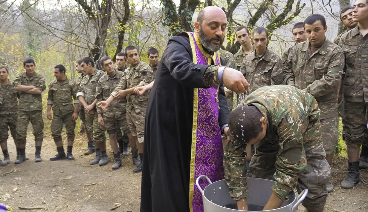 Pendeta Aristakes Hovhannisyan membaptis tentara Armenia di sebuah kamp militer dekat garis depan konflik di wilayah separatis Nagorno-Karabakh, Azerbaijan, Senin (2/11/2020). Pasukan Armenia dan Azerbaijan saling menyalahkan atas serangan baru selama perebutan Nagorno-Karabakh. (AP Photo)