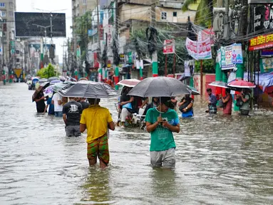 Orang-orang membawa payung menyeberangi jalan yang tergenang air di tengah curah hujan di Feni, Bangladesh pada Kamis 22 Agustus 2024. (Foto oleh AFP)