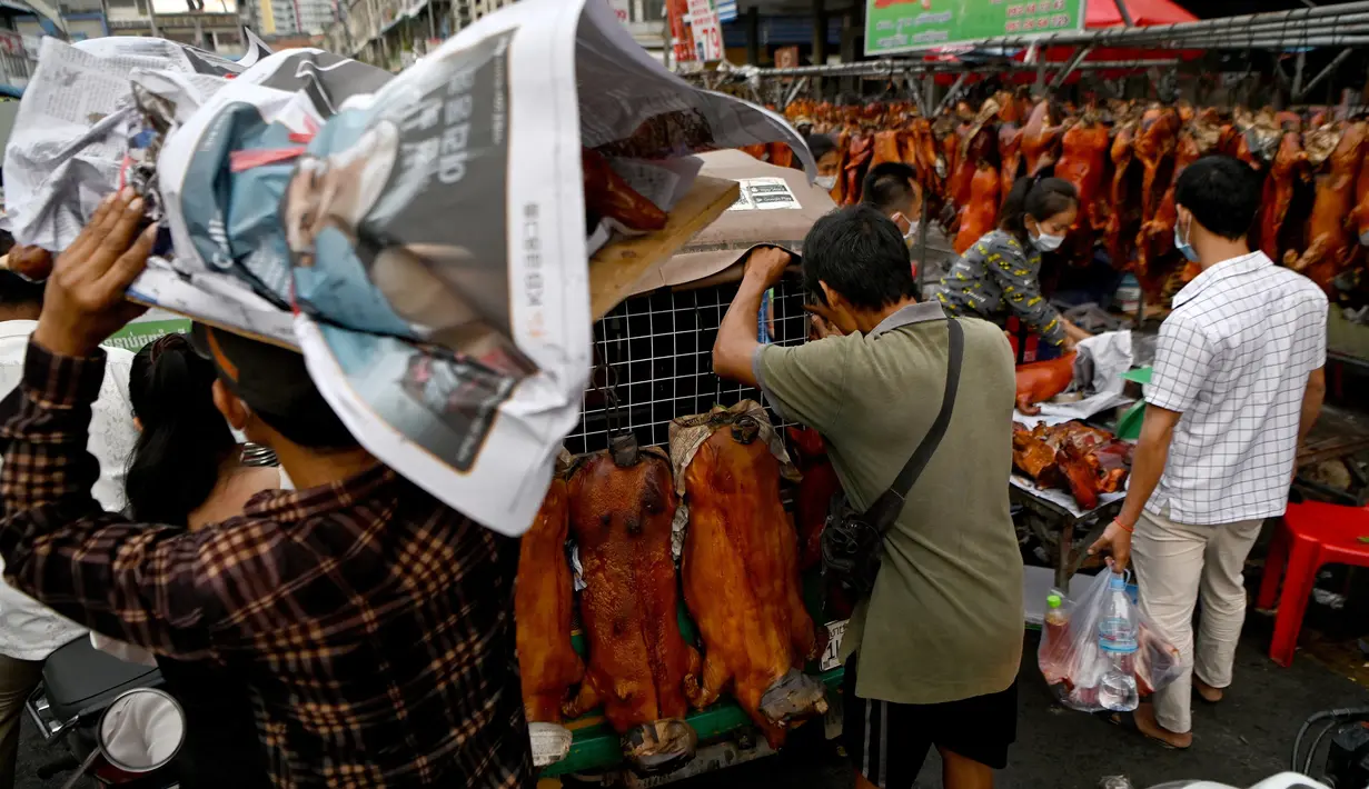 Seorang pria (kiri) membawa babi panggang yang dibungkus koran di pasar menjelang Tahun Baru Imlek di Phnom Penh, Kamboja, Senin (31/1/2022). Tahun Baru Imlek mengawali Tahun Macan pada 1 Februari. (AFP/Tang Chhin Sothy)