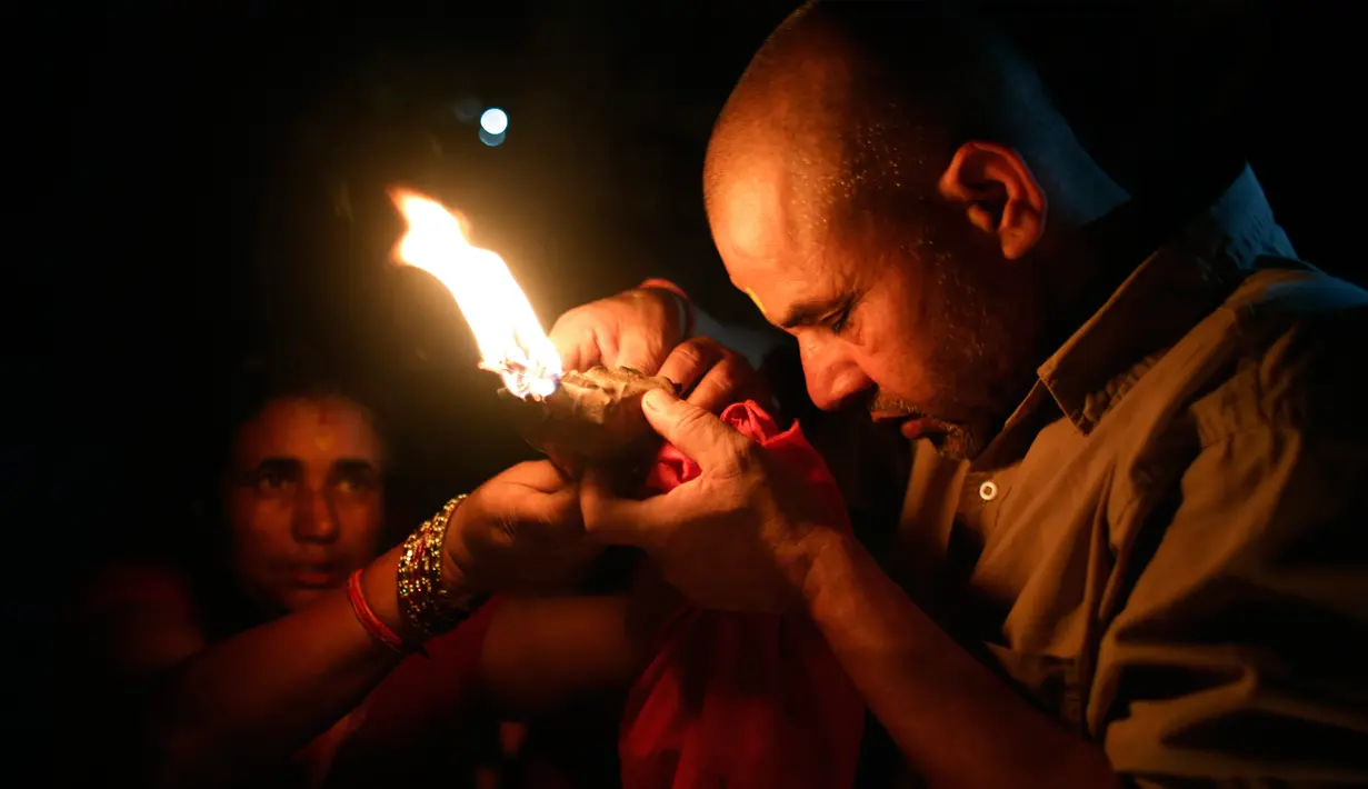 Seorang pria berdoa sambil memegang lampu minyak saat festival Kuse Aunsi di kuil Hindu Gokarneshwar, Kathmandu, Nepal (21/8). Kuse Aunsi sebagai bentuk penghormatan kepada Ayah atas bimbingan dan ajarannya dalam kehidupan. (Niranjan Shrestha/AP)