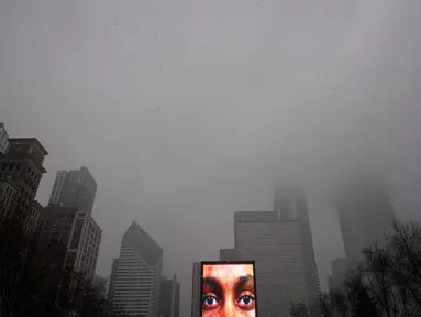 Mata dari wajah yang diproyeksikan pada salah satu dari dua monolit Crown Fountain terlihat saat langit kelabu di Millennium Park Chicago, Kamis (4/2/2021).  Badai musim dingin terus menambah salju yang sudah menumpuk di Chicago. (AP Photo/Charles Rex Arbogast)