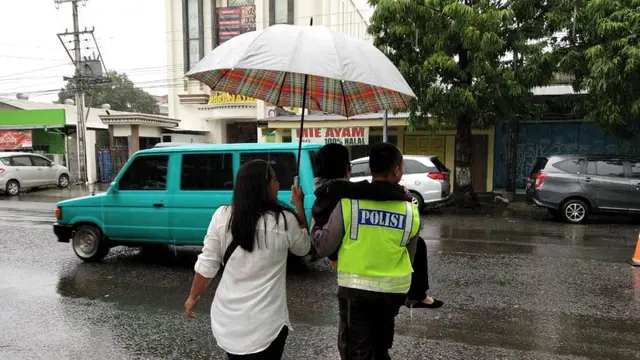 Seorang polisi menggendong nenek yang kehujanan ketika menyeberang ke gereja Maranatha, Cilacap. (Foto: Liputan6.com/Polres Cilacap/Muhamad Ridlo)