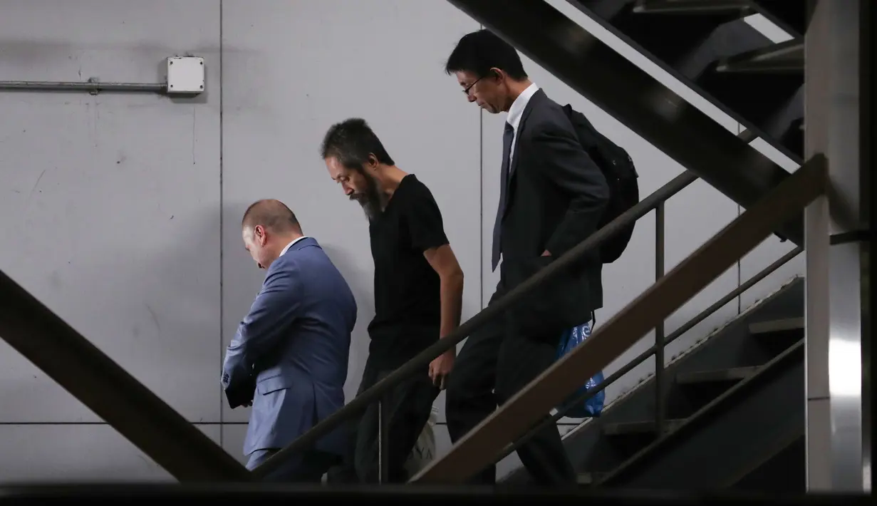 Jurnalis Jepang Jumpei Yasuda (tengah) menuruni tangga saat tiba dari Istanbul di bandara Narita di Prefektur Chiba (25/10). Jumpei disekap kelompok ekstremis di Suriah menggambarkan masa-masa itu sebagai "neraka". (AFP Photo/Behrouz Mehri)