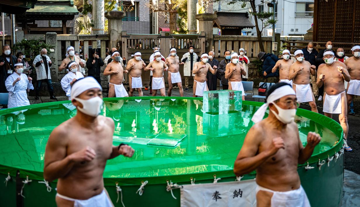 Penganut Shinto dari Kuil Teppozu Inari melakukan pemanasan sebelum mandi dengan air dingin untuk pemurnian jiwa selama ritual Tahun Baru di Tokyo, Jepang, Minggu (9/1/2022). Sejumlah pria mengenakan cawat tradisional dan wanita dengan jubah putih mengikuti ritual tersebut. (Philip FONG/AFP)