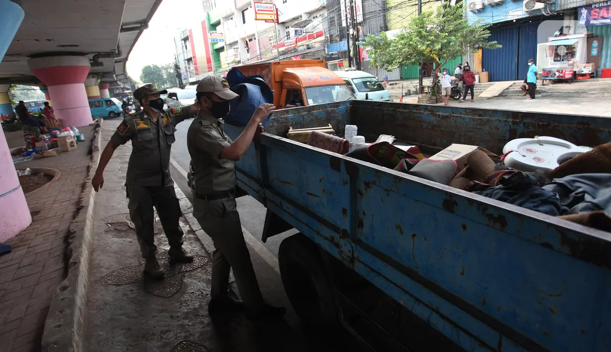 Petugas Satpol PP merapikan barang milik tunawisma di bawah flyover Jatinegara, Jakarta Timur, Senin (19/7/2021). Hal ini juga untuk mencegah terjadinya penyebaah virus Covid-19. (Liputan6.com/Johan Tallo)