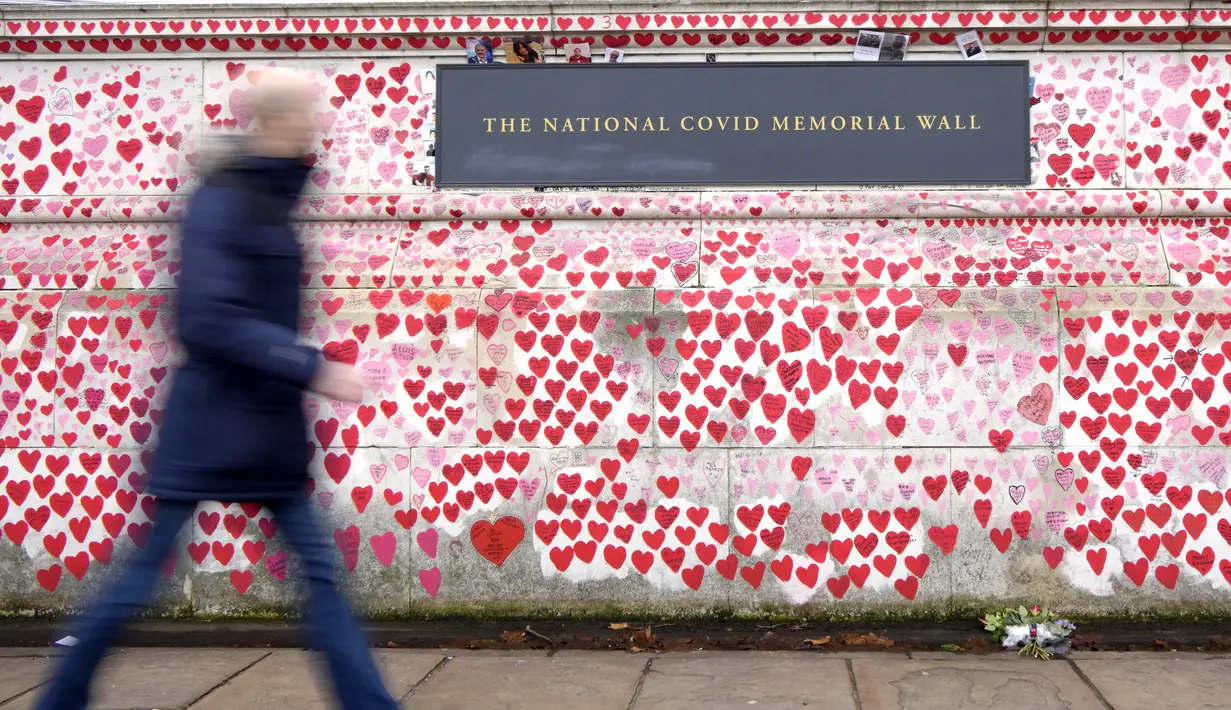 Seorang pejalan kaki melewati Tembok Memorial COVID di London, Senin (10/1/2022). Data menunjukkan, booster dosis kedua belum dibutuhkan karena saat ini vaksin dosis ketiga bagi orang di atas 65 tahun, telah memberikan perlindungan terhadap rawat inap sekitar 90 persen (AP Photo/Kirsty Wigglesworth)