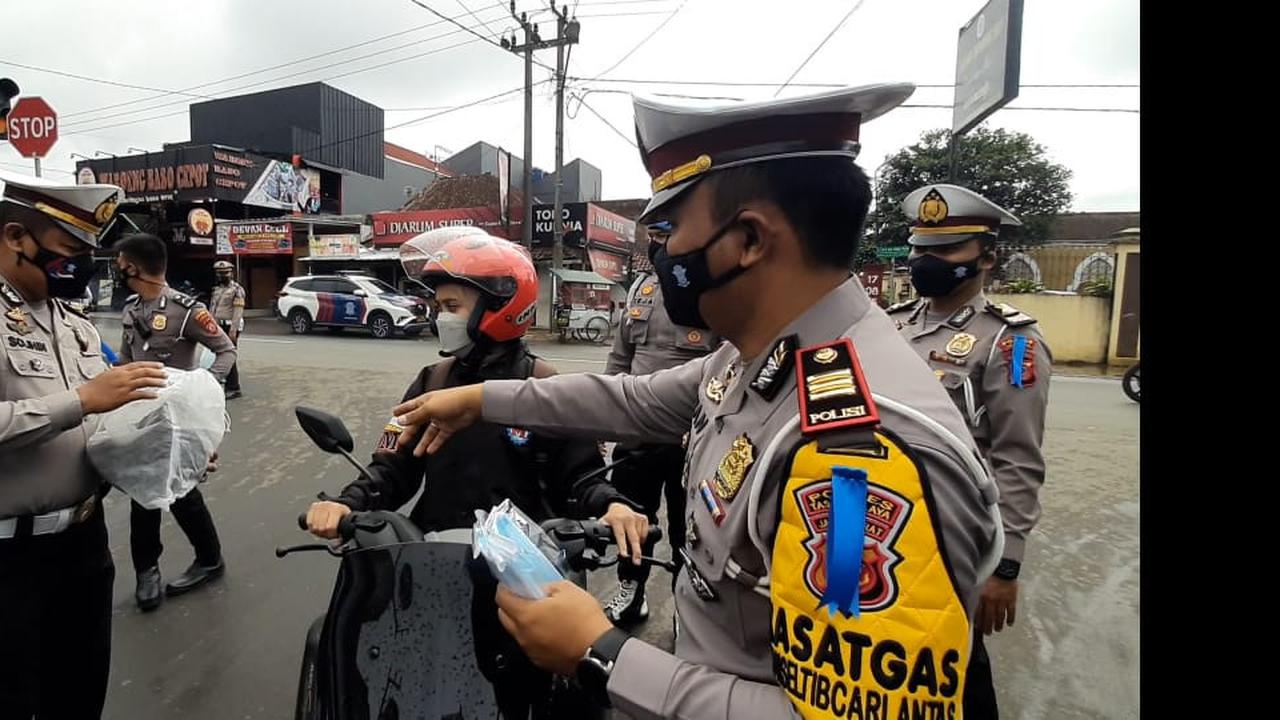 Petugas Polres Tasikmalaya, tengah memberikan reward helm bagi pengguna roda yang patuh menggunakan masker dan bersurat kendaraan lengkap, namun tidak berhelm, saat hari pertama operasi lodaya 2021.