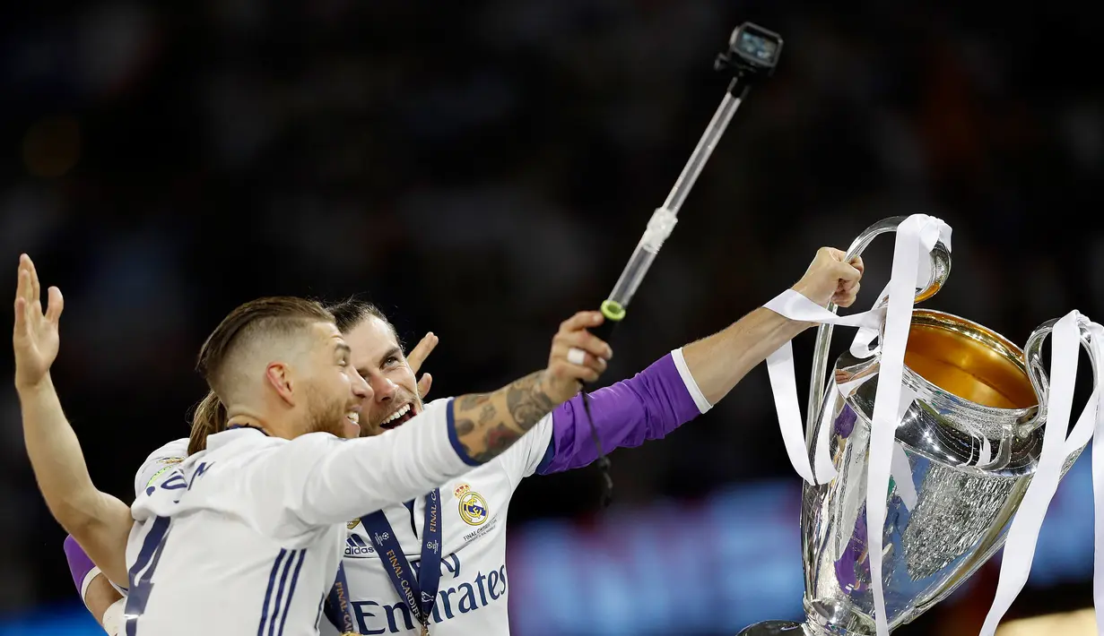 Kapten Real Madrid Sergio Ramos berswafoto bersama Gareth Bale sambil memegang piala usai Real Madrid memenangkan pertandingan Liga Champions di Stadion Cardiff, Wales (3/6). (AFP Photo/Adrian Dennis)