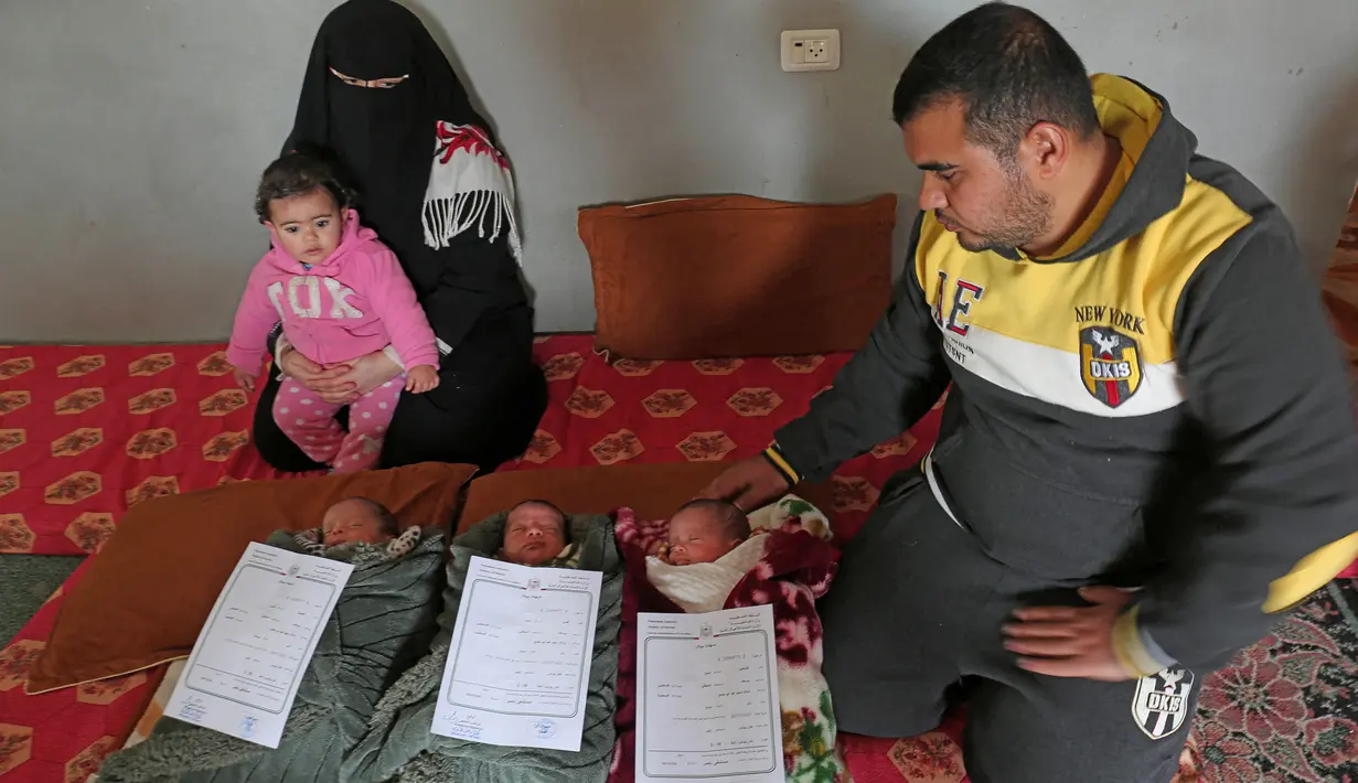 Pasangan Nidal dan Islam Al-Saiqli berpose dengan bayi kembar mereka, Jerusalem, Capital dan Palestine di Khan Yunis, Jalur Gaza, Jumat (2/2). Pasangan Nidal dan Islam memberi nama unik kepada tiga bayi kembar mereka yang baru lahir. (SAID KHATIB/AFP)