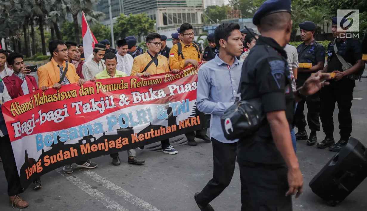Peserta aksi yang tergabung dalam Mahasiswa dan Pemuda Relawan Cinta NKRI membagikan takjil ke anggota Polri yang bertugas di Gedung Bawaslu RI, Jakarta, Minggu (26/5). Aksi simpatik sebagai wujud apresiasi kepada anggota Polri-TNI yang menjaga keamanan aksi 22 Mei 2019. (Liputan6.com/Faizal Fanani)