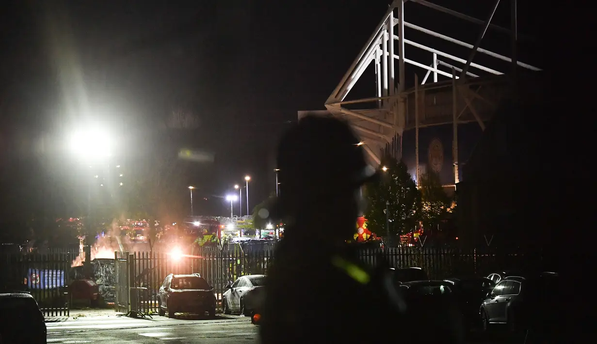 Petugas berjaga di dekat helikopter yang jatuh dan terbakar di tempat parkir di luar Stadion King Power, Leicester, Inggris (27/10). Saksi mata mengatakan beberapa polisi sempat berusaha menyelematkan orang di dalam helikopter. (AFP Photo/Ben Stansall)