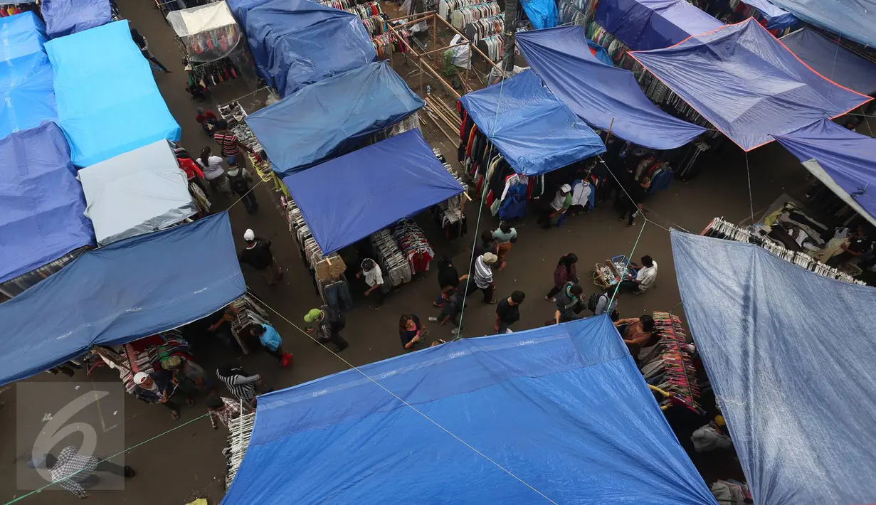 Pengunjung melewati pedagang korban kebakaran yang berjualan di area parkir Pasar Senen, Jakarta, Rabu (8/2). Belum tersedianya tempat penampungan sementara membuat para pedagang terpaksa mendirikan tenda lapak. (Liputan6.com/Immanuel Antonius)