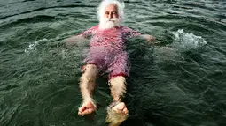 Seorang sinterklas bersantai di air pada pada hari kedua Konvensi Musim Panas Sinterklas ke-59 di Kopenhagen, Denmark, 19 Juli 2016. Mereka memulai pagi hari dengan berenang di pantai Bellevue. (Mathias Loevgreen Bojesen/Scanpix Denmark/AFP)
