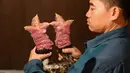 Peternak unggas Le Van Hien memegang kaki ayam Dong Tao di peternakannya di Provinsi Hung Yen, Vietnam, 10 Januari 2023. Ayam Dong Tao memang memiliki postur tubuh yang sehat dan kaki gemuk dengan ditutupi sisik kemerahan. (Nhac NGUYEN/AFP)