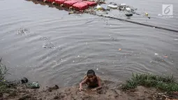 Anak-anak berjalan di tumpukan sampah di kawasan Banjir Kanal Barat, Petamburan, Jakarta, Jumat (9/11). Mendung yang menyelimuti ibukota Jakarta, tidak menyurutkan anak-anak bermain di Sungai Banjir Kanal Barat. (Liputan6.com/Fery Pradolo)