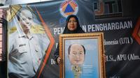 Istri Sutopo sedang menunjukkan karikatur bergambar suaminya yang diberikan IJTI, Kamis (11/7).(Liputan6.com/Fajar Abrori)