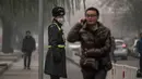 Petugas mengenakan masker saat kabut asap menyelimuti Beijing, China, Senin (30/11). Pemerintah setempat mengumumkan keadaan siaga dan menyarankan warga Beijing untuk berada dalam rumah karena kandungan polusi udara yang berbahaya. (AFP PHOTO/FRED DUFOUR)