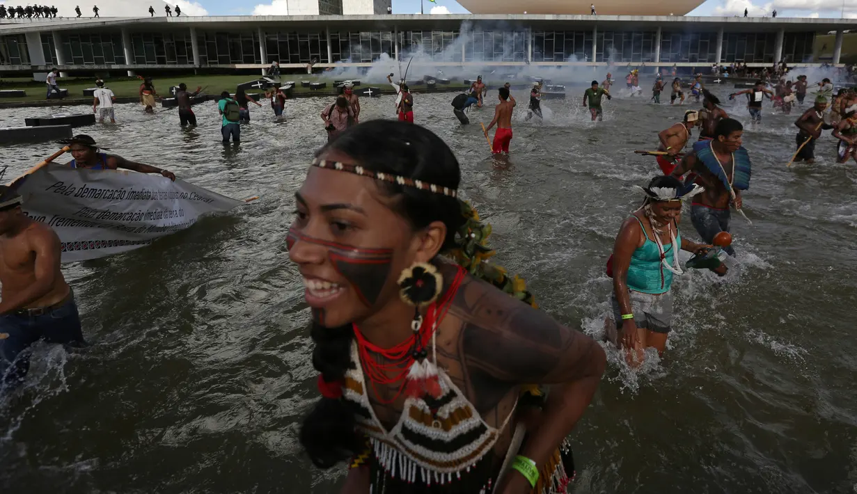 Sejumlah orang dari suku asli Brasil menceburkan diri di kolam gedung Kongres Nasional saat menggelar aksi, Brasilia, Brasil (25/4). Mereka berusaha menyelamatakan diri dari tembakan gas air mata dengan menceburkan diri ke kolam. (AP Photo/Eraldo Peres)