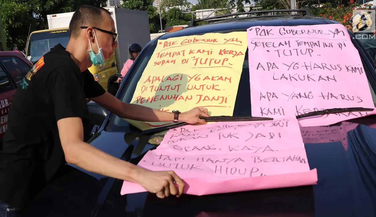 Karyawan Hotel Alexis menempelkan poster tuntutan di mobil Satpol PP saat unjuk rasa di Jakarta Utara, Kamis (29/3). Penutupan terkait kasus dugaan adanya praktek prostitusi dan perdagangan manusia di hotel tersebut. (Liputan6.com/Immanuel Antonius)
