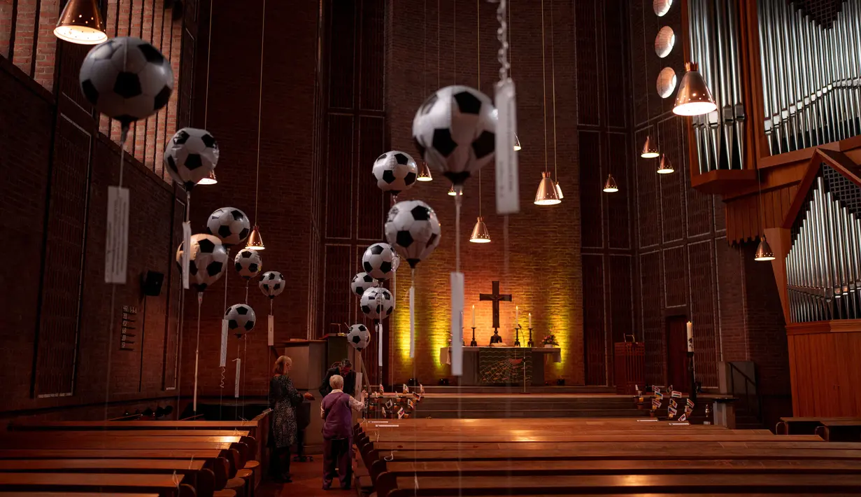 Orang-orang meniup balon bertema sepak bola di Gereja Evangelis Emaus di Gelsenkirchen, Jerman, Minggu, 23 Juni 2024. (AP Photo/Alessandra Tarantino)
