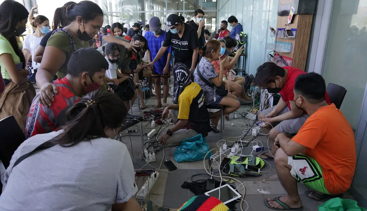 Warga mengisi daya ponsel mereka secara gratis di sebuah mal saat sebagian besar kota Cebu masih tanpa listrik akibat Topan Rai, Sabtu (18/12/2021). Badai menghantam beberapa daerah berpenduduk padat, termasuk Cebu Kamis malam, satu kota berpenduduk hampir 1 juta orang. (AP/Jay Labra)