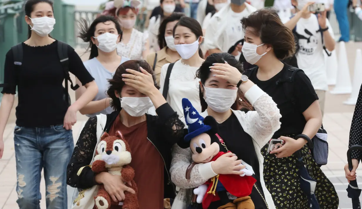 Pengunjung mengenakan masker guna melindungi diri dari virus corona berjalan menuju pintu masuk Tokyo Disneyland di Urayasu, dekat Tokyo, Rabu (1/7/2020). Tokyo Disneyland dibuka kembali untuk pertama kalinya dalam empat bulan setelah menangguhkan operasi karena kekhawatiran Covid-19. (AP/Koji Sasah