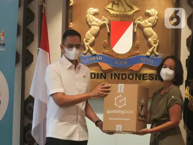 Senior Communication Manager GudangAda, Muara Makarim (kanan) secara simbolis menyerahkan paket sembako kepada Ketua Pelaksana Vaksinasi Keliling yang juga Wakil Ketua Umum Bidang Komunikasi dan Informatika KADIN Firlie H (kiri) di Jakarta, Senin (11/10/2021). (Liputan6.com/HO/Agus)