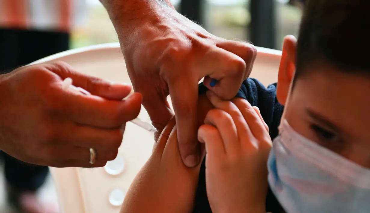 Seorang anak disuntik vaksin covid-19 CoronaVac selama kampanye vaksinasi di San Lorenzo, Paraguay, Senin (31/1/2022). Paraguay mulai memvaksinasi anak-anak berusia 5 hingga 11 tahun pada hari Senin, karena peningkatan tajam infeksi covid-19 yang didorong oleh varian omicron. (NORBERTO DUARTE / AFP)