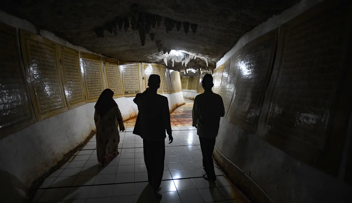 Pengunjung berjalan sambil mengamati ayat-ayat Al Quran yang ditempel pada dinding Gua di Desa Cinangneng, Tenjolaya, Kabupaten Bogor, Jawa Barat, Selasa (11/3/2025). (merdeka.com/Arie Basuki)