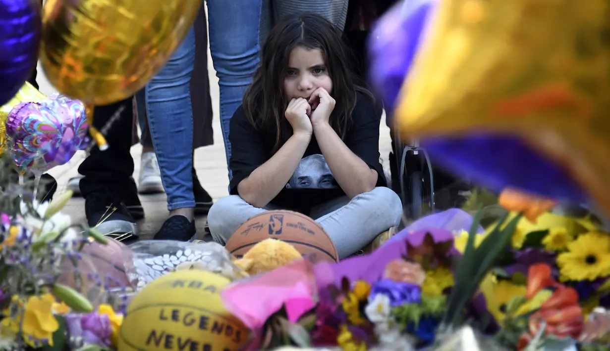 Seorang anak saat menghadiri acara penghormatan untuk Kobe Bryant dan putrinya Gianna di luar Staples Center, Los Angeles, California (28/1/2020). Kobe Bryant meninggal bersama putrinya Gianna dalam kecelakaan helikopter di Calabasas, California. (Kevork Djansezian/Getty Images/AFP)