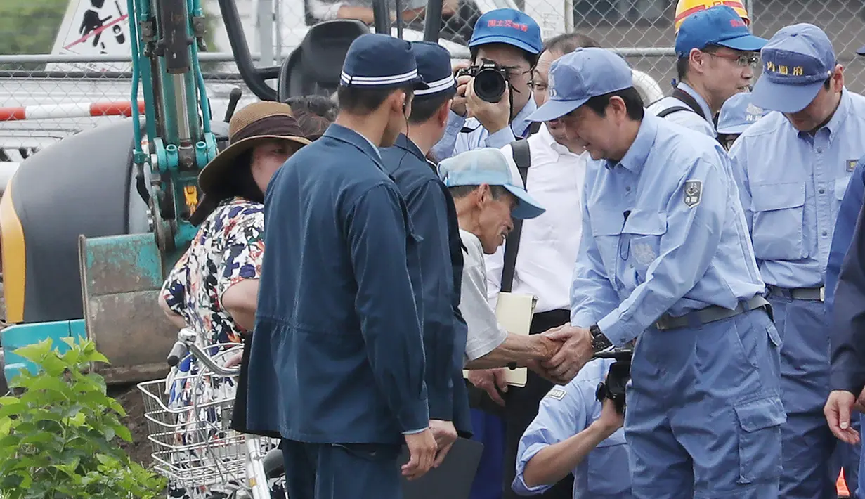 PM Jepang Shinzo Abe bertemu warga yang terkena dampak banjir saat mengunjungi wilayah Hita di prefektur Oita, Rabu (12/7). Abe menunjukkan keprihatinan dan berusaha untuk berinteraksi secara langsung dengan orang-orang di lokasi. (STR/JIJI PRESS/AFP)