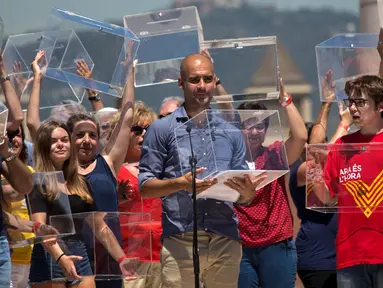Pelatih Manchester City Pep Guardiola memegang kotak surat dalam aksi menuntut kemerdekaan Catalonia, di Barcelona, Minggu (11/6). Catalonia secara sepihak merencanakan menggelar referendum untuk berpisah dari Spanyol pada 1 Oktober. (AP/Emilio Morenatti)
