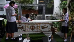 Seorang siswa remaja mencoba masuk ke dalam peti mati di Kid Mai Death Awareness Cafe, Thailand (30/3). Selain itu cafe ini juga menyediakan menu yang cukup aneh seperti minuman rasa "kematian" dan "menyakitkan". (AFP/Lillian Suwanrumpha)