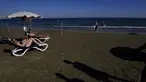 Sepasang suami istri menikmati cuaca hangat di pantai Makenzi di selatan kota Larnaca, Siprus, Senin (8/11/2021). Siprus mengalami cuaca seperti musim panas dalam beberapa hari terakhir dengan suhu tinggi yang tidak sesuai musim dan langit cerah. (AP Photo/Petros Karadjias)