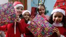 Sejumlah anak Palestina mengenakan kostum santa claus sambil membawa kado berpose saat perayaan menyambut Hari Natal di Sekolah Amerika di Kota Gaza (20/12).  (AFP Photo/Mohammed Abed)