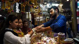 Seorang wanita Pakistan mencoba gelang di pasar menjelang Hari Raya Idul Fitri di Karachi (3/6/2019). Umat Muslim di seluruh dunia sedang bersiap untuk merayakan Hari Raya Idul Fitri, yang menandai akhir bulan puasa Ramadan. (AFP Photo/Asif Hassan)