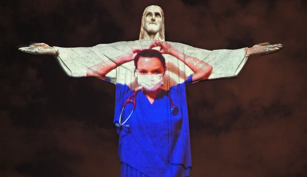 Patung Christ the Redeemer atau Yesus sang Penebus yang populer di dunia menyala dengan gambar tenaga medis pada Paskah di Rio de Janeiro, Brasil, Minggu (12/4/2020). Pertunjukkan itu bentuk solidaritas kepada dokter dan perawat yang telah merawat pasien corona di berbagai negara. CARL DE SOUZA/AFP)