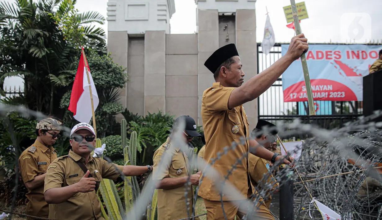Seorang kepala desa memberikan isyarat saat melakukan aksi di depan Gedung DPR RI, Jakarta, Selasa (17/1/2023). Dalam aksi yang diikuti ribuan orang tersebut mereka menuntut perpanjangan masa jabatan kepala desa yang sebelumnya enam tahun menjadi sembilan tahun dan meminta DPR RI merevisi masa jabatan yang diatur dalam UU Nomor 6 Tahun 2014 tentang Desa. (Liputan6.com/Faizal Fanani)