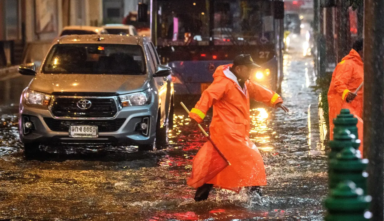 Petugas keamanan mengatur lalu lintas di jalan yang banjir saat hujan deras di Bangkok (23/9/2020). (AFP/Mladen Antonov)