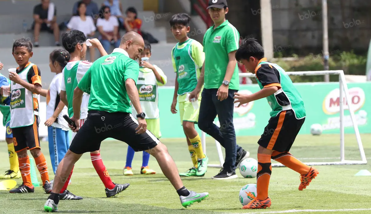 Mantan striker Timnas Indonesia, Kurniawan Dwi Yulianto, beradu skill dengan seorang anak pada acara Milo Football Clinic di Lapangan Sepak Bola Pertamina, Simprug, Jakarta, Minggu (24/4/2016). (Bola.com/Nicklas Hanoatubun)