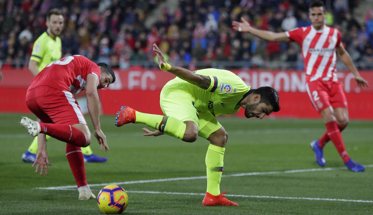 Striker Barcelona, Luis Suarez, berebut bola dengan pemain Girona, Borja Garcia, pada laga La Liga di Stadion Montilivi, Minggu (27/1). Barcelona menang 2-0 atas Girona. (AP/Manu Fernandez)