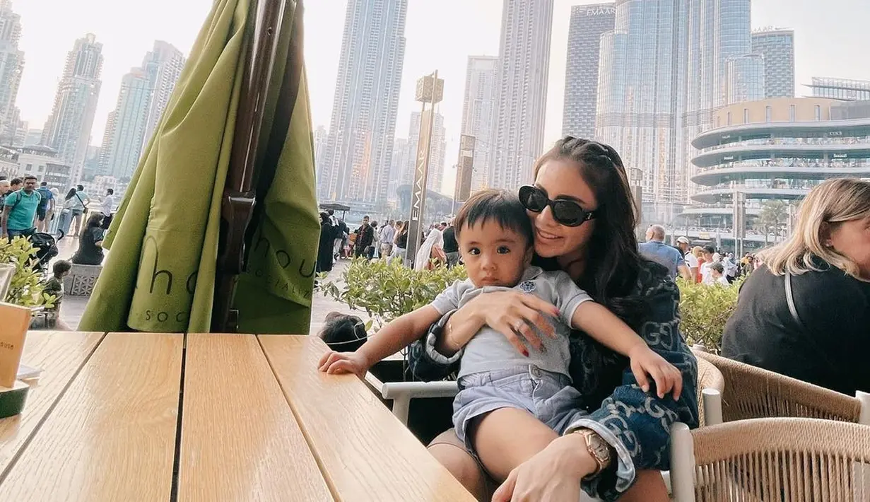 Kali ini, Momo tampak memangku sang buah hati. Bergaya stylish, Momo tampak mengenakan jaket, sunglasses, dan menata rambut panjangnya bak remaja. Foto: Instagram.