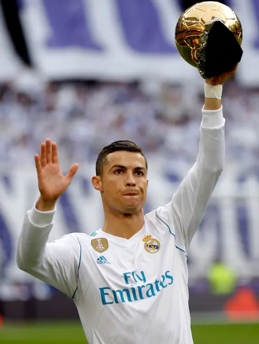 Pemain Real Madrid, Cristiano Ronaldo memamerkan trofi bola emas Ballon d'Or sebelum laga Real Madrid vs Sevilla di Stadion Santiago Bernabeu, Sabtu (9/12). Jumlah trofi Ballon d'Or Ronaldo saat ini setara dengan milik Lionel Messi. (AP/Francisco Seco)