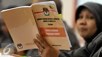 Anggota KPU membaca buku Undang-Undang tentang Penyelenggaraan Pemilihan Umum saat menghadiri acara Uji Publik Pilkada Serentak 2017 di Gedung KPU, Jakarta, Senin (18/7). (Liputan6.com/Johan Tallo)